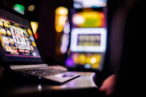 A woman smiling by bright slot machines showing lucky symbols, showcasing the exciting slot offerings at 3777 BED.